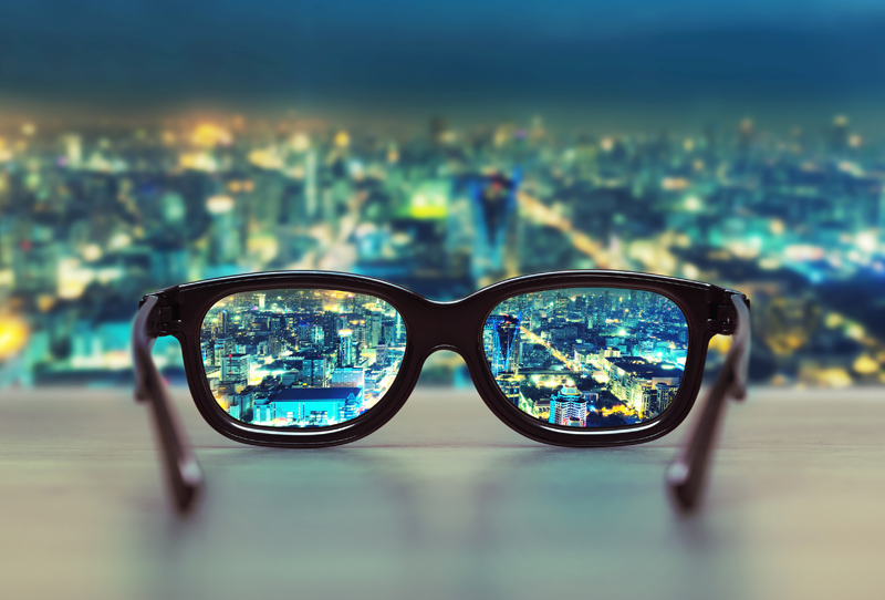 Night cityscape focused in glasses lenses. Vision concept